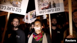 Israeli left wing demonstrators march holding placards protesting the right wing incitement against President Reuven Rivlin and human rights activists in Tel Aviv. December 19, 2015. An ultra-nationalist Israeli group has published a video accusing the heads of four of Israel's leading human rights organisations of being foreign agents funded by Europe and supporting Palestinians "involved in terrorism". The sign reads, "That's how occupation looks like." 