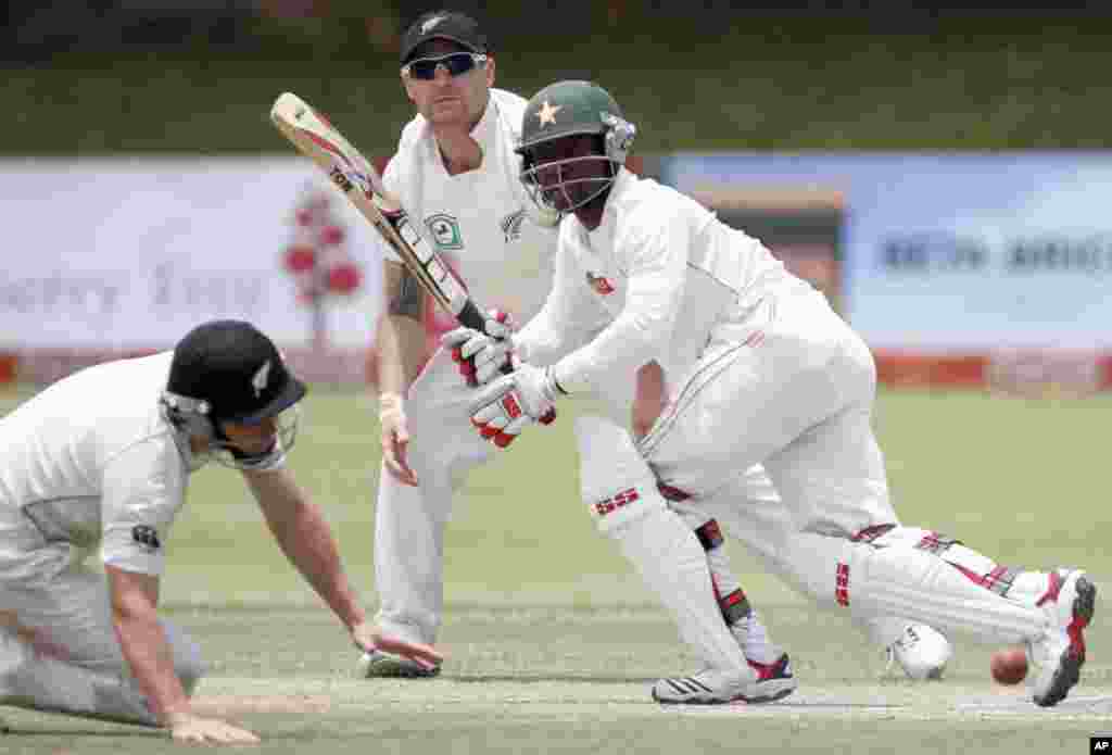 Zimbabwe's batsman Tatenda Taibu (R) plays a shot, as New Zealand's Doug Bracewell (L) and Brendon McCullum watch, during the third day of their test cricket match in Bulawayo November 3, 2011. REUTERS/Philimon Bulawayo (ZIMBABWE - Tags: SPORT CRICKET)