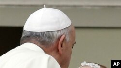 Le pape François porte un bébé au Vatican, mercredi, 15 octobre 2014.