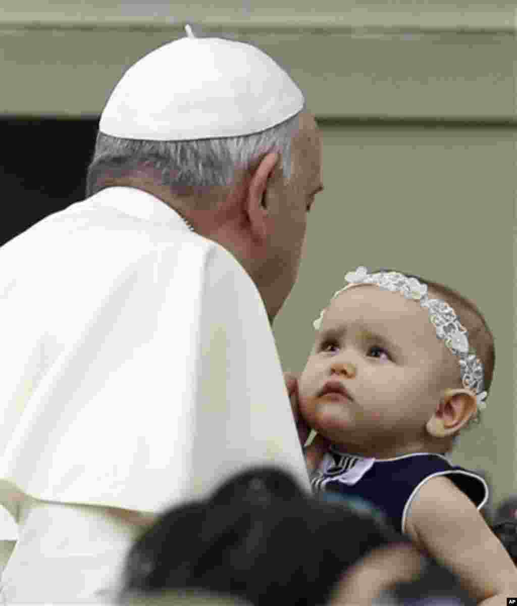 Pape Francois caresse un bébé dans la place Saint-Pierre où il arrive pour assister à l&#39;audience générale hebdomadaire au Vatican, le mercredi 15 octobre 2014 (AP Photo / Gregorio Borgia) 