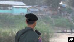 Thai soldier watches people who fled fighting take boats to and from Burma, Mae Sot, Thailand, 09 Nov 2010