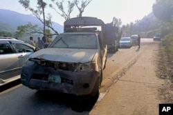 Kendaraan melaju melewati kendaraan polisi yang rusak, saat mengawal konvoi diplomat asing, di jalan dekat Malam Jabba, kawasan wisata di provinsi Khyber Pakhtunkhwa, Pakistan, Minggu, 22 September 2024. (Sherin Zada/AP)