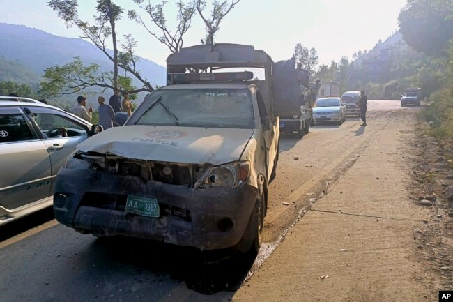 Kendaraan melaju melewati kendaraan polisi yang rusak, saat mengawal konvoi diplomat asing, di jalan dekat Malam Jabba, kawasan wisata di provinsi Khyber Pakhtunkhwa, Pakistan, Minggu, 22 September 2024. (Sherin Zada/AP)