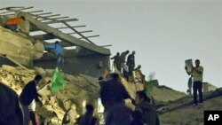 Moammar Gadhafi supporters inspect damage following an airstrike in Tripoli, Libya, April 25, 2011