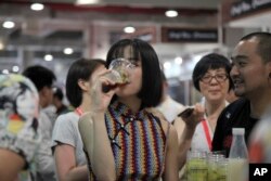 A woman drinks beer at the 2018 Craft Beer of China Exhibition in Shanghai, May 17, 2018.