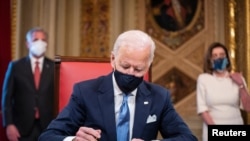 Новый президент США Джо Байден подписывает первые документы в специальной комнате президента на Капитолии. 20 января 2021 года.