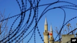 Turkish and Turkish Cypriot breakaway flags are seen through the barbed wires by the U.N. buffer zone that divides the Greek and Turkish Cypriots controlled areas, in the divided capital Nicosia, Mediterranean island of Cyprus, Jan. 12, 2017.