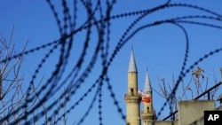 Bendera Turki dan Siprus Turki di kubah masjid Selimiye atau Agia Sofia, terlihat dari pagar kawat di wilayah penyangga PBB di Siprus (12/1).(AP/Petros Karadjias)