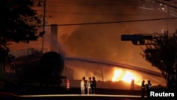 Firefighters look at a train wagon on fire at Lac Megantic, Quebec, July 6, 2013.