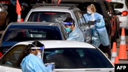 Medical personnel take details at a drive-through COVID-19 testing station in Melbourne on August 19, 2021.