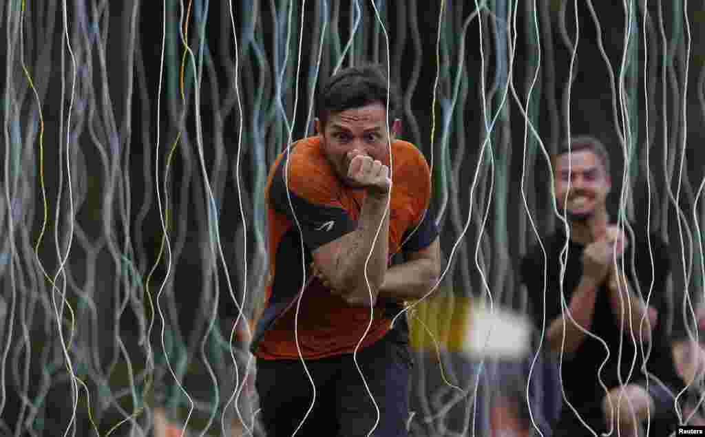 Participants run through the &quot;Electroshock Therapy&quot; obstacle made of hanging electrical wire holding some 10,000 volts in the finish of the &quot;Tough Mudder&quot; endurance event series in Arnsberg, Germany, Sept. 6, 2014.