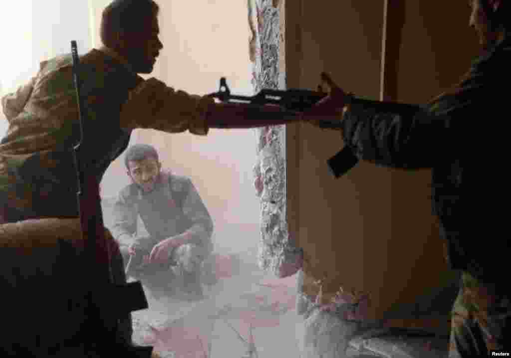 A Free Syrian Army fighter passes an AK-47 rifle to his fellow fighter in Aleppo, Syria, August 14, 2012. 