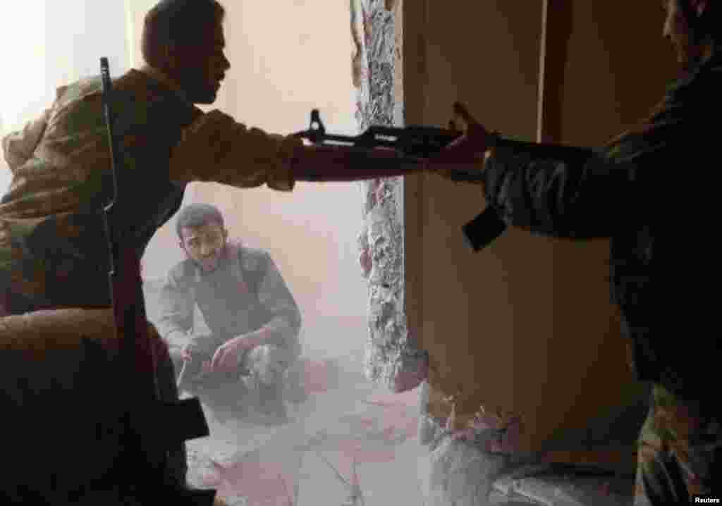A Free Syrian Army fighter passes an AK-47 rifle to his fellow fighter in Aleppo, August 14, 2012. 