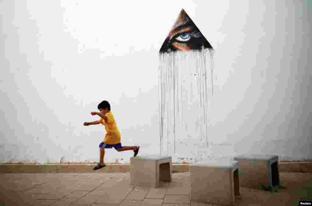 A boy plays in front of a wall painting by Hawaiian artist Kamea Hadar during an art and culture festival called POW! WOW! Israel, in the southern city of Arad, Israel.