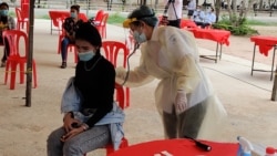 A garment worker returning from her hometown for the Khmer New Year holiday is checked for COVID-19 at Chumpou Vorn high school, Phnom Penh, Cambodia, April 20, 2020. (Nem Sopheakpanha/VOA Khmer)