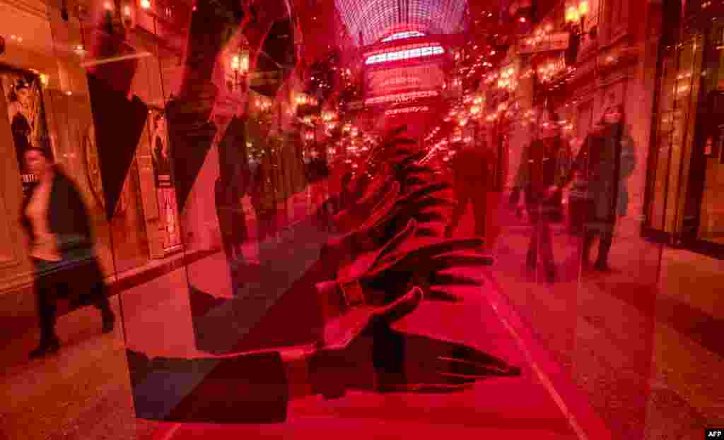 People walk past a watch store advertisement at the GUM department store in downtown Moscow, Russia.