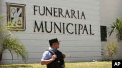 A municipal police officer stands outside the Municipal Funeral Home at La Bermeja Cemetery, where the bodies of Óscar Alberto Martínez Ramírez, 25, and his daughter Valeria, 23 months, arrived in San Salvador, El Salvador, June 30, 2019.