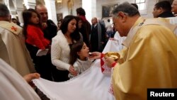 A Palestinian girl receives communion from the Latin Patriarch of Jerusalem Fouad Twal at the Church of St. Catherine, which is connected to the Church of Nativity, in the West Bank town of Bethlehem on Christmas day, Dec. 25, 2013. 