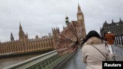 A woman holds her umbrella during a gust of wind on Westminster Bridge after Storm Darragh hit the country, in London on Dec. 7, 2024.