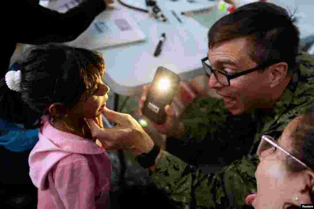 Kamila, the daughter of Yenymar Vilches, a Venezuelan migrant, is attended to by personnel of the ship of the United States Navy Hospital USNS Comfort at Divina Pastora High School in Riohacha, Colombia, Nov. 26, 2018.