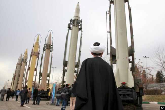 FILE - An Iranian clergyman looks at domestically built surface-to-surface missiles displayed by the Revolutionary Guard in a military show marking the 40th anniversary of the Islamic Revolution, at Imam Khomeini Grand Mosque in Tehran, Iran, Feb. 3, 2019.