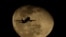 FILE - A passenger jet passes in front of a waning moon after taking off from Phoenix Sky Harbor International Airport, in Phoenix, Arizona, Feb. 11, 2020. Jill Marie Jones was arrested there last week before she could leave the country.