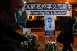 People wearing masks attend a vigil for the late Li Wenliang, an ophthalmologist who died of coronavirus at a hospital in Wuhan, in Hong Kong, Feb. 7, 2020.
