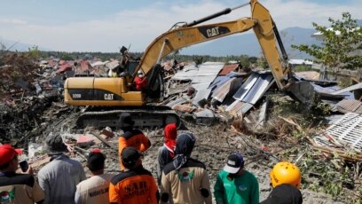 Tim pengelamat menggunakan alat berat untuk membersihkan puing-puing bangunan pasca gempa dan tsunami di Palu, Jumat (5/10).