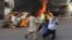 Pakistani volunteers and local residents carry the dead body of a protester beside a burning car after gunmen opened fire on a rally in Karachi, May 22, 2012.