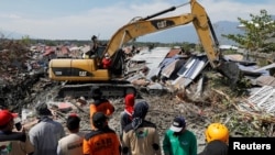 Tim pengelamat menggunakan alat berat untuk membersihkan puing-puing bangunan pasca gempa dan tsunami di Palu, Jumat (5/10).