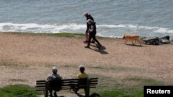 FILE - Elderly people walk on Avon Beach as the spread of the coronavirus disease (COVID-19) continues, Christchurch, Britain, April 21, 2020.