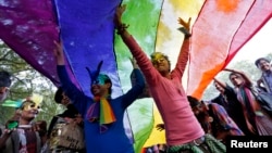 FILE - Participants dance under a a rainbow flag as they attend the sixth Delhi Queer Pride parade, an event promoting gay, lesbian, bisexual and transgender rights, in New Delhi, November 24, 2013.