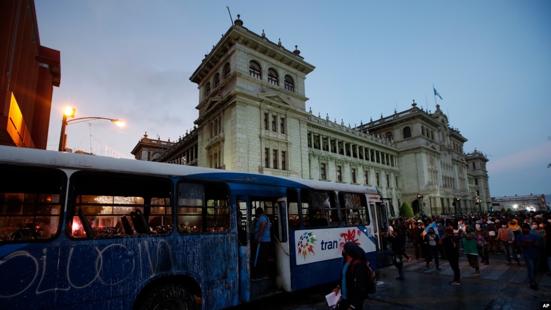 Manifestantes se acercan a un autobús dañado por manifestantes frente al Palacio Nacional para exigir la renuncia del presidente Alejandro Giammattei, en la Ciudad de Guatemala, el sábado 28 de noviembre de 2020. 