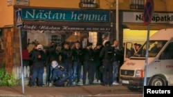 Masked men are lined up against a wall by riot police in a Stockholm suburb, on the sixth straight night of riots, May 25, 2013. 