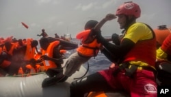 Des agents de l’ONG espagnole Proactiva Open Arms secourent des migrants en plein Méditerranée, à près de 15 miles au nord de Sabratha, Libye, 25 juillet 2017.