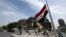 The Syrian flag flies at half-staff in Damascus on May 20, 2024, after the death of Iran's president in a helicopter crash. A car bomb exploded on May 25 in the Damascus neighborhood where the Iranian consulate was located before it was destroyed last month in an aerial attack.