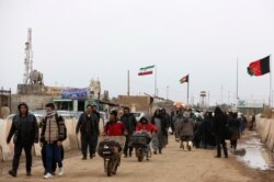 FILE - Afghans return to Afghanistan at the Islam Qala border with Iran, in western Herat province, Feb. 20, 2019.