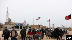 FILE - Afghans return to Afghanistan at the Islam Qala border with Iran, in the western Herat Province, Feb. 20, 2019.