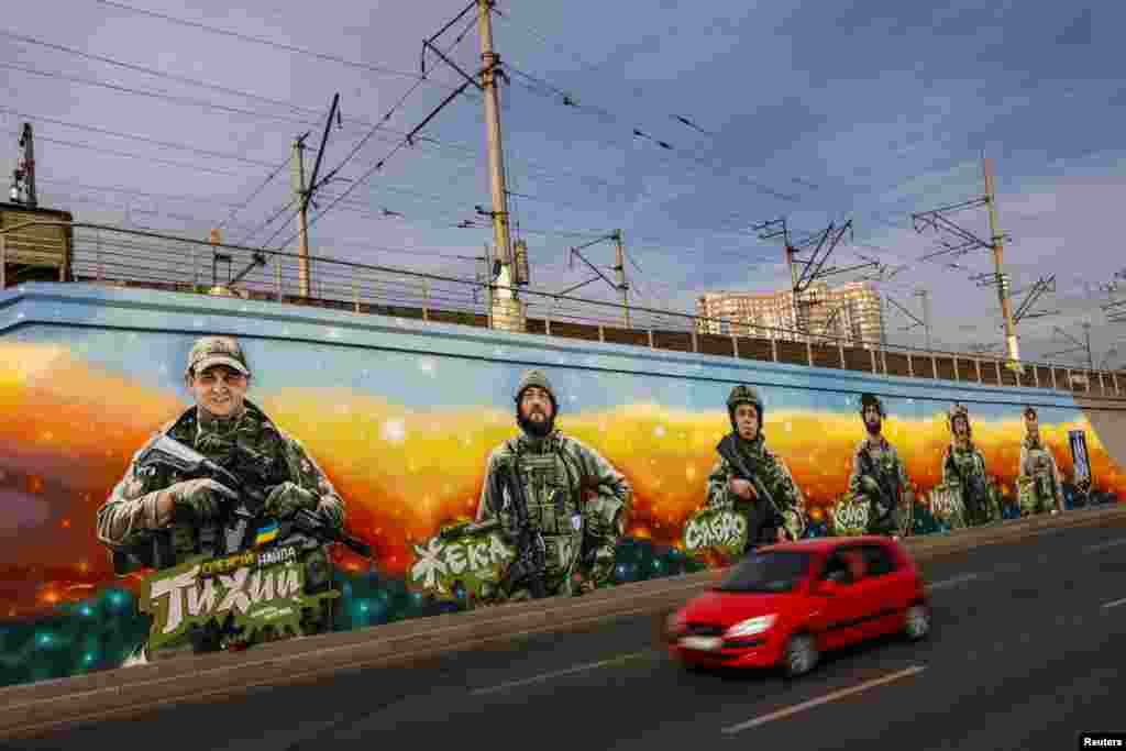 Un automóvil pasa junto a los murales de soldados ucranianos caídos de la unidad Gonor de los &quot;Lobos Da Vinci&quot; del Primer Batallón Separado que fue creado por el artista callejero ucraniano Eugene Gladenko, en medio del ataque de Rusia a Ucrania, en Kiev, Ucrania, el 4 de octubre de 2024.&nbsp;