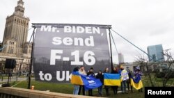 Para demonstran pro-Ukraina berdemo di depan Hotel Marriot, tempat Presiden AS Joe Biden menginap di Warsawa, Polandia. Mereka meminta AS mengirim jet-jet tempur F-16 untuk membantu Ukraina melawan invasi Rusia, 22 Februari 2023. (Foto: Alesandra Szmigiel/Reuters)