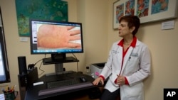 Dermatologist Dr. Anne Burdick checks the computer screen in her Miami office, as she discusses telemedicine, 2014. (AP Photo/J Pat Carter)