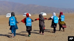 Afghan schoolgirls hold hands and walk towards their tent classrooms on the outskirts of Jalalabad, capital of Nangarhar province, Dec. 13, 2016. 