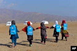 FILE - Afghan schoolgirls hold hands and walk towards their tent classrooms on the outskirts of Jalalabad, capital of Nangarhar province, Afghanistan, Dec. 13, 2016.