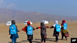 Afghan schoolgirls hold hands and walk towards their tent classrooms on the outskirts of Jalalabad, capital of Nangarhar province, Afghanistan, Dec. 13, 2016. 