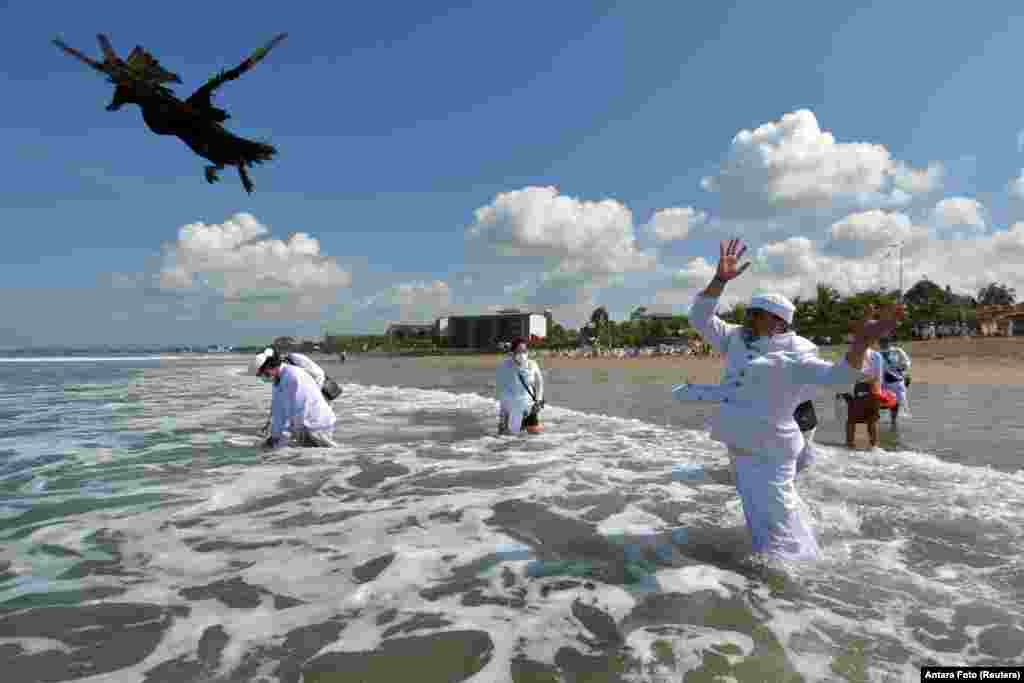 A Balinese Hindu worshiper throws a duck as he prays at a beach during a Melasti purification ceremony ahead of the holy day of Nyepi in Badung, Bali, Indonesia.