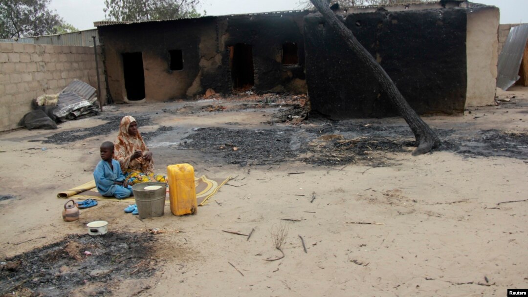 Seorang ibu dan anaknya duduk di luar rumah yang terbakar hangus akibat konflik antara pasukan Nigeria dan militan di Nigeria utara (foto; dok). 