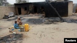 Seorang ibu dan anaknya duduk di luar rumah yang terbakar hangus akibat konflik antara pasukan Nigeria dan militan di Nigeria utara (foto; dok). 