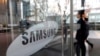 FILE - An employee walks past the Samsung Electronics Co. logo at its office in Seoul, Jan. 31, 2018. This month, two former Samsung employees were sentenced to two years in prison for trying to leak Samsung’s OLED secrets to China.