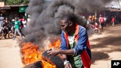 A protesters reacts next to a burning barricade during a mass rally called by the opposition leader Raila Odinga over the high cost of living in Kibera Slums, in Nairobi, March 27, 2023. 