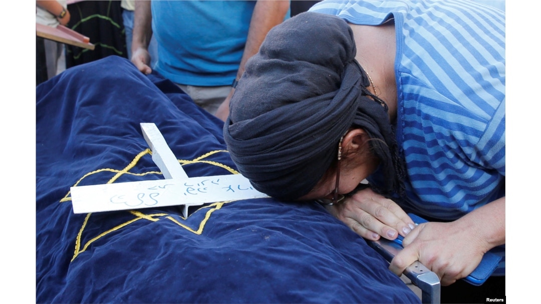 FILE - The mother of Israeli girl, Hallel Yaffa Ariel, 13, who was killed in a Palestinian stabbing attack in her home in the West Bank Jewish settlement of Kiryat Arba, mourns during her daughter's funeral at a cemetery in the West Bank city of Hebron, June 30, 2016.